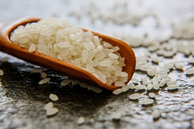 Wooden scoop filled with white rice grains